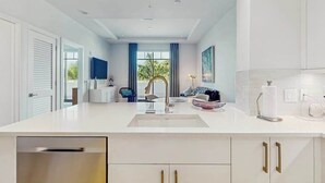 A modern kitchen with a central island, white cabinetry, and a view to the outside. - Exceptional condo with balcony, WIFi, and located close to beaches and downtown (Naples)