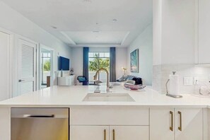 A modern kitchen with a central island, white cabinetry, and a view to the outside. - Exceptional condo with balcony, WIFi, and located close to beaches and downtown (Naples)