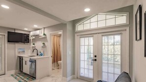A modern kitchen with a built-in dishwasher, a small island, and a flat-screen TV above the counter. - Spacious home private heated pool, fireplace, & two kitchens-near downtown (Naples)