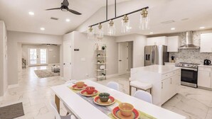 A modern kitchen with a central island, white cabinetry, and a ceiling fan. - Spacious home private heated pool, fireplace, & two kitchens-near downtown (Naples)