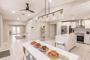 A modern kitchen with a central island, white cabinetry, and a ceiling fan. - Spacious home private heated pool, fireplace, & two kitchens-near downtown (Naples)