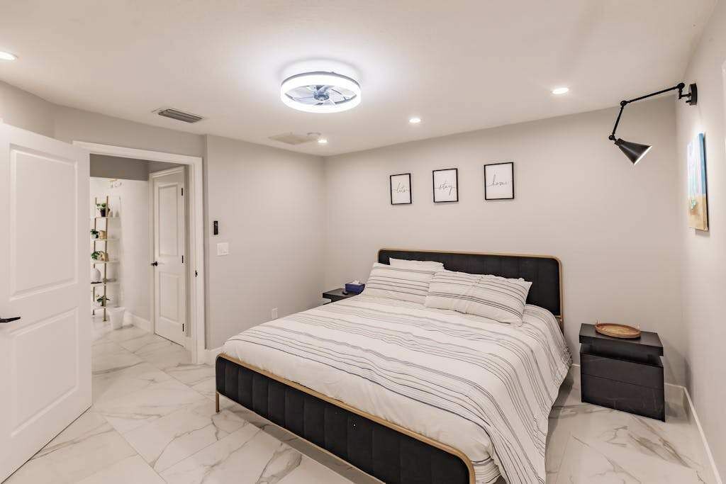 A bedroom with a bed, bedside tables, a ceiling light, and framed pictures on the wall.