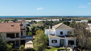Un quartier résidentiel où les maisons se distinguent par leurs toits recouverts de tuiles rouges, un ciel d’un bleu éclatant et une vue lointaine sur la mer.
