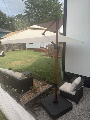 A patio with outdoor furniture, a pergola, and a white wall.