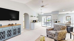 A modern living room with a flat-screen TV, a patterned armchair, and a wooden coffee table. - Snowbird Friendly Waterfront Escape with Private Pool, Dock & Serene Canal Views (Port Charlotte)