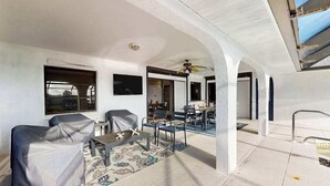 An interior space with a ceiling fan, covered chairs, a dining area, and a view through an open archway. - Snowbird Friendly Waterfront Escape with Private Pool, Dock & Serene Canal Views (Port Charlotte)