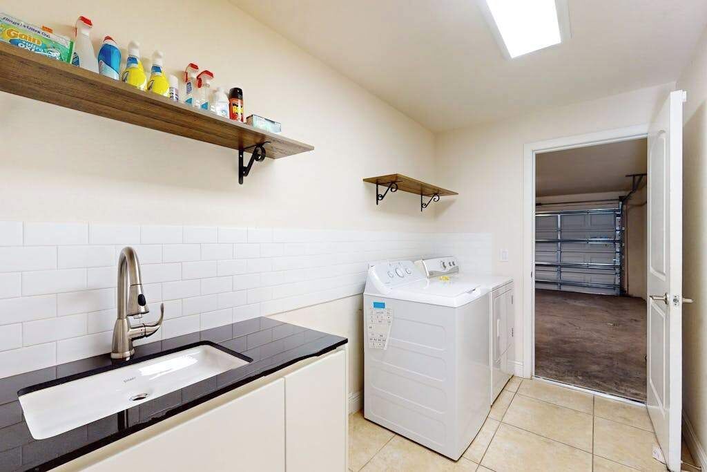 Una cuina compacta amb un rentaplat, una rentadora i dues prestatgeries murals amb productes de neteja.