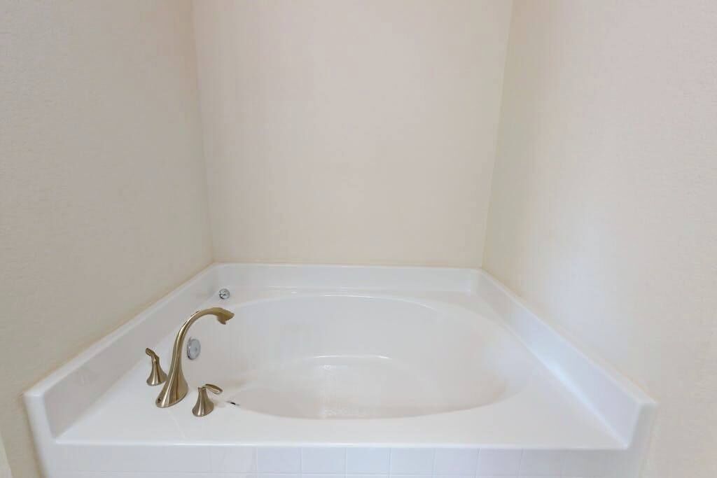 Une baignoire blanche avec un seul robinet, placée dans un coin de la pièce.
