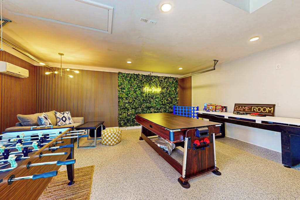 A room with a foosball table, a pool table, and a game room sign.