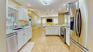 Una cocina moderna con armarios blancos, electrodomésticos de acero inoxidable y una isla central.