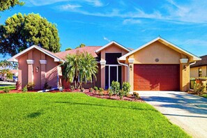 Una casa residencial con garaje, entrada para vehículos y césped bien cuidado.
