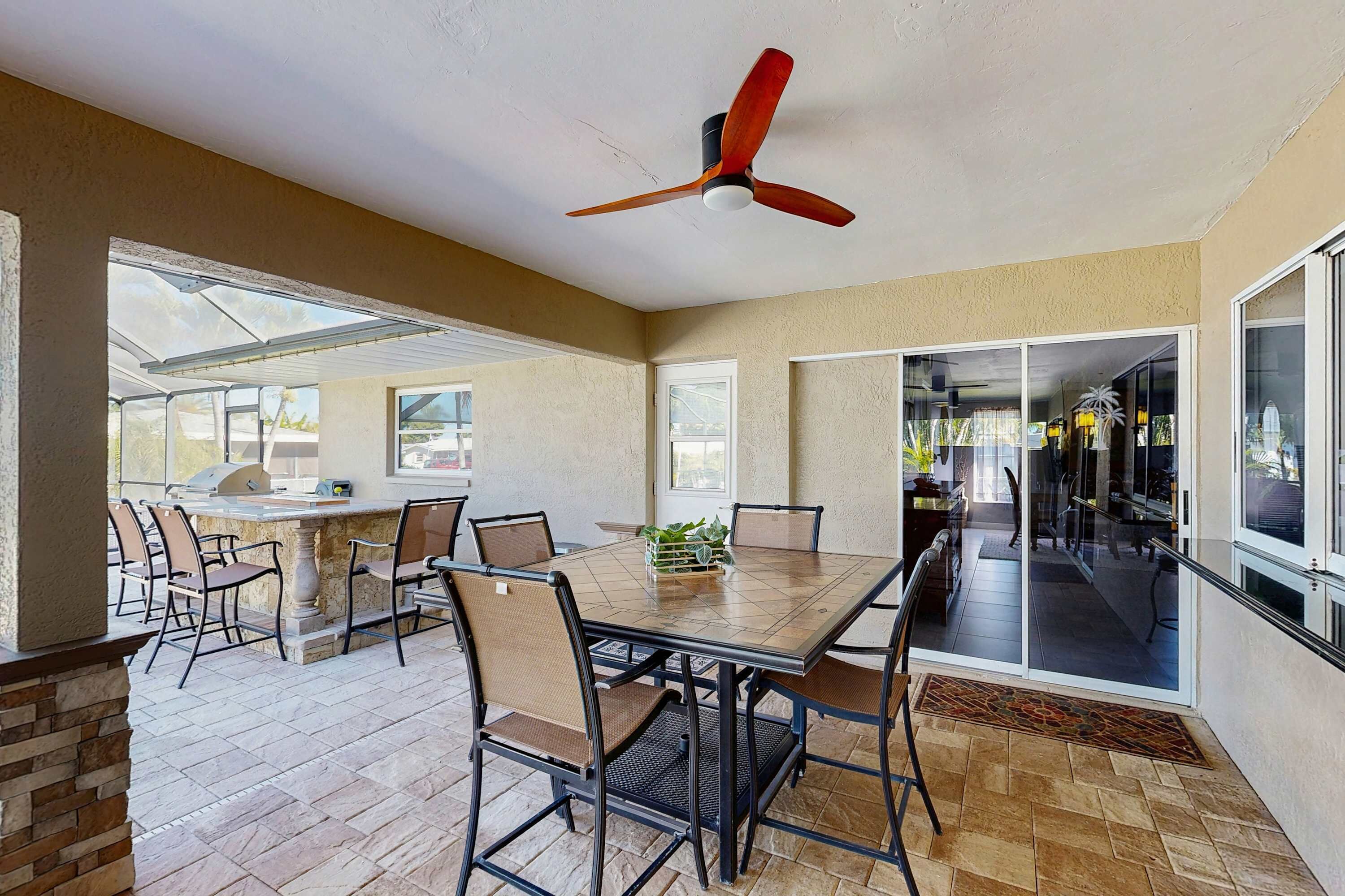 Patio esterno con tavolo, sedie e ventilatore a soffitto.