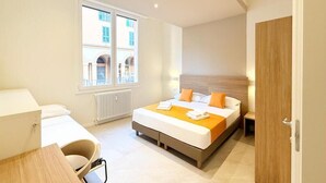Una habitación de hotel moderna con cama, escritorio, silla, ventana y puerta.