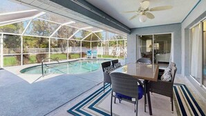 A covered outdoor swimming pool with a table and chairs, a ceiling fan, and a view of the backyard. - Dog-friendly home w/private salt water in ground pool & close to Shamrock Park (Venice)