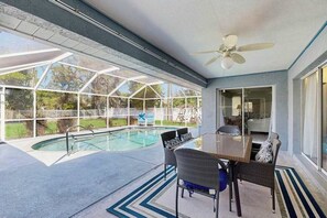 A covered outdoor swimming pool with a table and chairs, a ceiling fan, and a view of the backyard. - Dog-friendly home w/private salt water in ground pool & close to Shamrock Park (Venice)