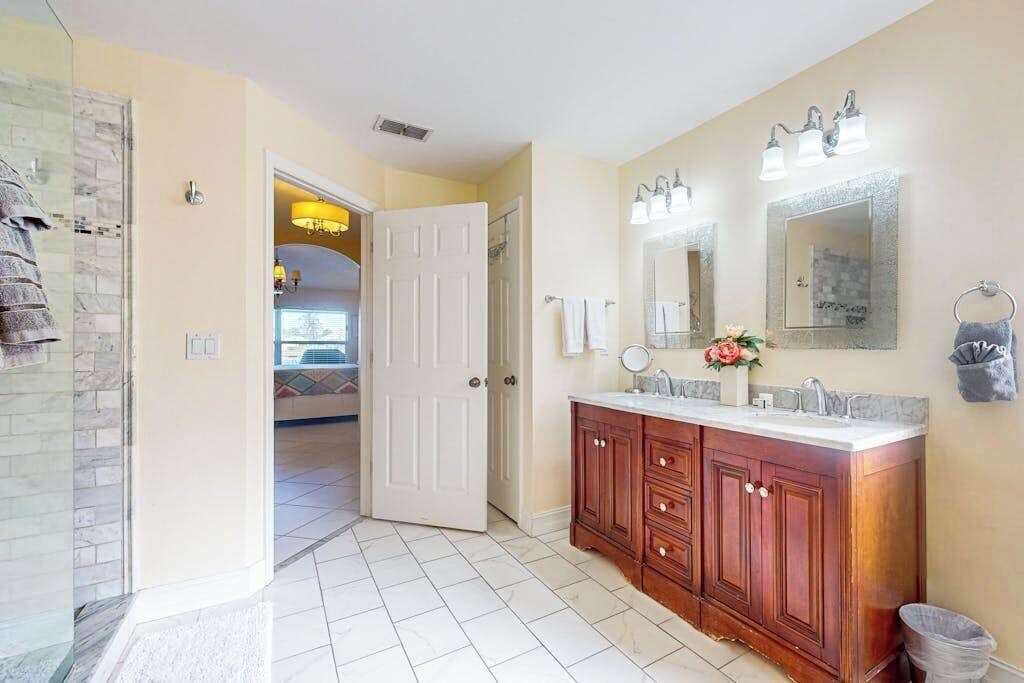 A bathroom with a wooden vanity, a large mirror, and a shower area.