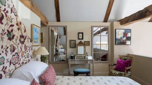 Ein Schlafzimmer mit einem Bett, einem Schminktisch, einem Spiegel und einem Stuhl.