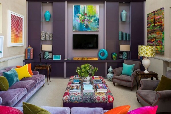 A living room with a sofa, armchairs, a coffee table, and a TV.