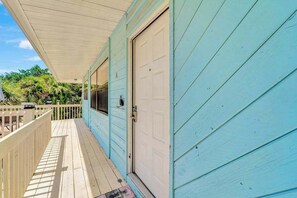 Une terrasse en bois dotée d’un espace abrité, d’une porte et d’une fenêtre.