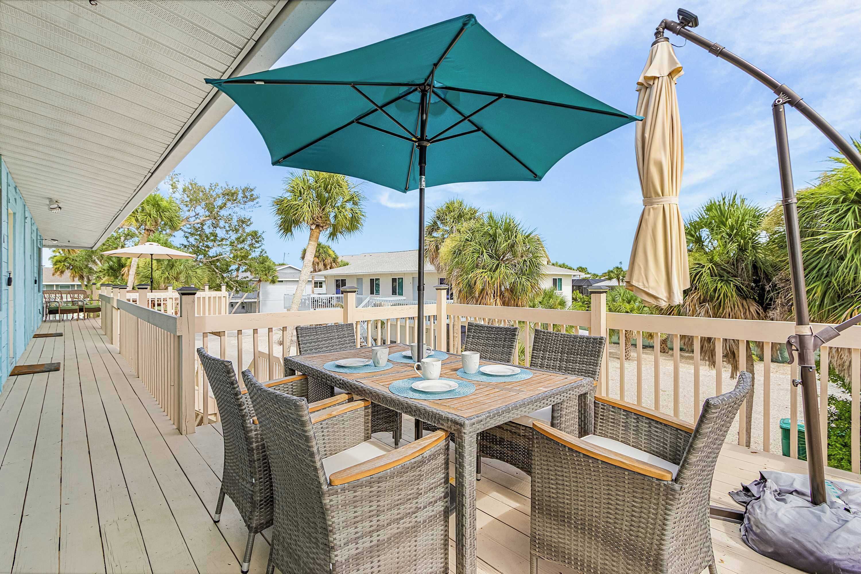 An outdoor patio with a table and chairs, a large umbrella, and a view of the surrounding area.
