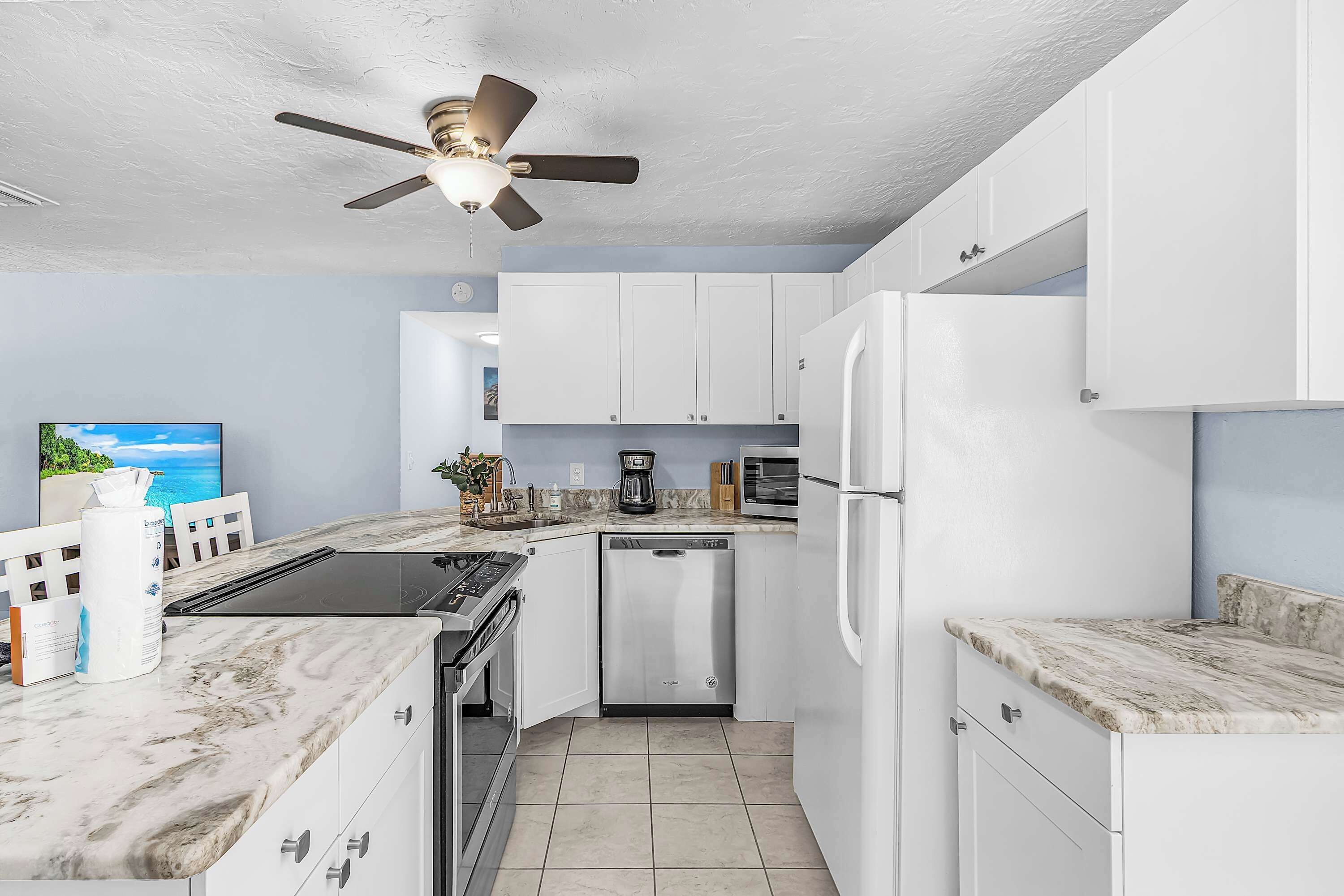 A modern kitchen with white cabinets, a built-in oven, a dishwasher, and a refrigerator.