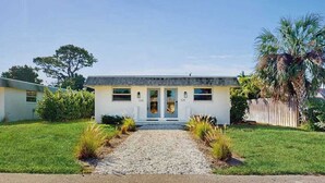 A single-story house with a front entrance, a gravel driveway, and a wooden fence. - Spacious master duplex w full kitchen, close to beach & shopping (Naples)