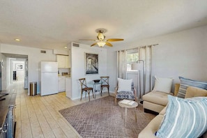A compact living space with a kitchenette, a dining area, a sofa, and a ceiling fan.