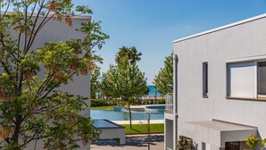 A modern building with a swimming pool, a clear sky, and greenery. - Talea Sun Sea Haven 1BR Apartment (Shënkoll)