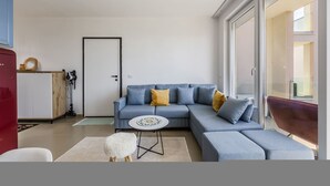 Una sala moderna con un sofá modular, una mesita redonda y un taburete blanco mullido.