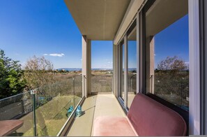 A balcony with a clear view of the landscape, a glass railing, and a pink chair. - Golden Hour Balcony Apartment Pool Beach 100m (Shënkoll)