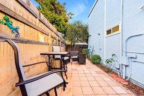 Eine Terrasse mit Gartenmöbeln, einem Holzzaun und einem blauen Gebäude.