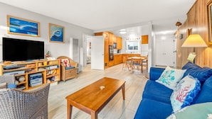 A living room with a TV, wooden furniture, a dining area, and a kitchen. - 25% Off Sept WkDays Great 4 Families, Walk 2 Beach (Ventura)
