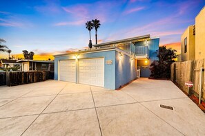 A modern two-story house with a garage, a balcony, and a wooden fence.