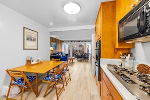 A compact kitchen with a dining area, wooden cabinets, and a built-in microwave.