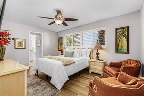 A bedroom with a bed, bedside tables, a ceiling fan, and framed artwork on the walls. - Beautiful home located on the canal w/gulf access, in ground pool, & wifi (Cape Coral)