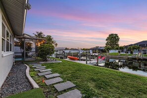 A waterfront property with a covered patio, a dock, and a small boat. - Beautiful home located on the canal w/gulf access, in ground pool, & wifi (Cape Coral)