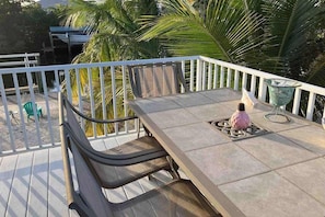 A balcony with a table and chairs, a glass container, and a view of palm trees. - Boat, Swim and Relax at Your Private Gulf Access Retreat (Saint James City)