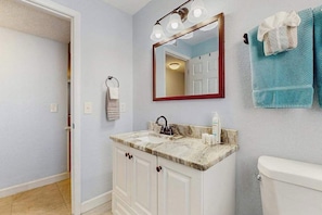 Ein Badezimmer mit Waschbecken, Spiegel, Handtuchhalter und Toilette.