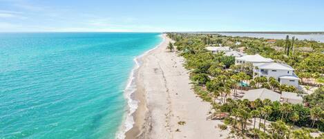 A coastal property with a beachfront, multiple buildings, and a clear view of the ocean.