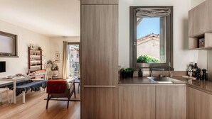 Une cuisine moderne dotée d’une grande fenêtre, de meubles en bois et d’un coin repas avec une table et des chaises.
