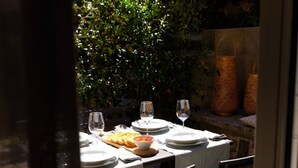 Un espace de restauration en plein air avec une table dressée pour deux personnes, entourée de verdure.