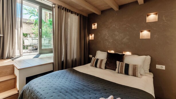 Une chambre avec un grand lit, une fenêtre avec des rideaux et des appliques murales encastrées.