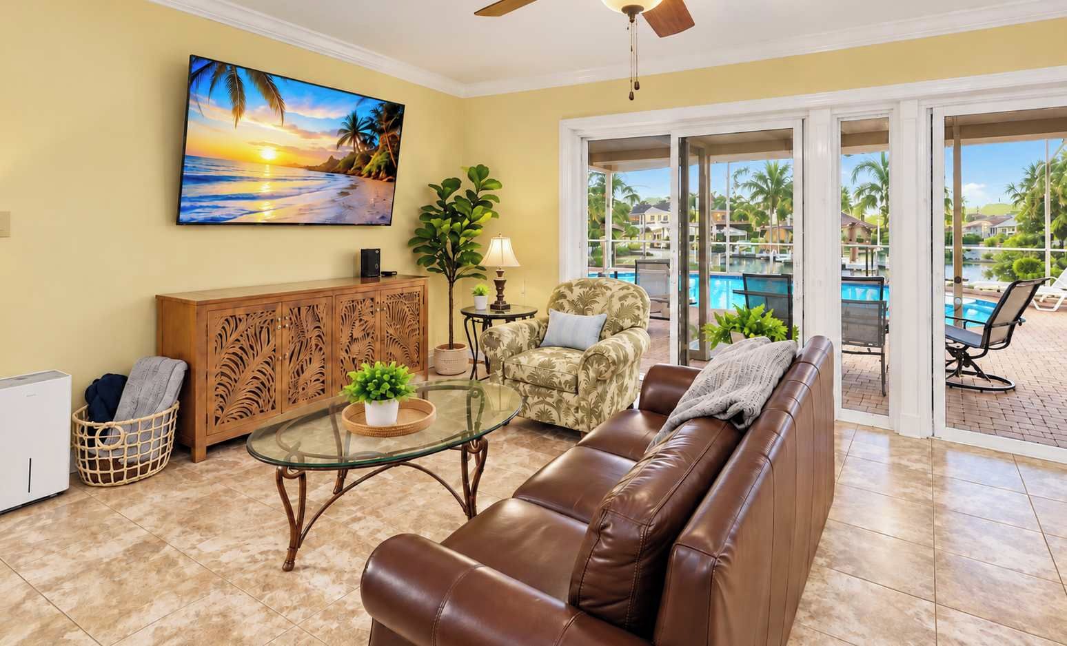 Un salon avec une table basse en verre, un canapé en cuir et un tableau représentant une scène de plage.