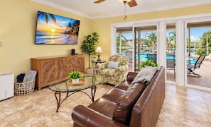 A living room with a glass coffee table, leather sofa, and a painting of a beach scene. - Perfect Family Canalfront Getaway (Cape Coral)