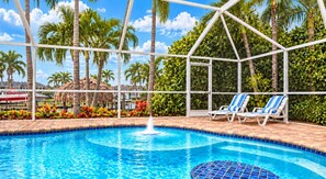 A swimming pool with a fountain, surrounded by palm trees and lounge chairs. - Perfect Family Canalfront Getaway (Cape Coral)