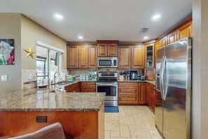 A kitchen with wooden cabinets, stainless steel appliances, and a granite countertop. - Gorgeous waterfront home with private pool, dock and outdoor space (Marco Island)