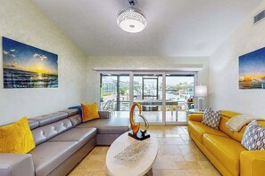 A modern living room with a grey sofa, a yellow sofa, and a coffee table with a sculpture. - Gorgeous waterfront home with private pool, dock and outdoor space (Marco Island)