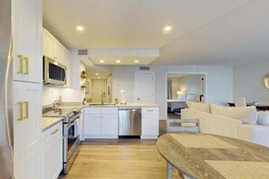 A modern kitchen with white cabinets, a microwave, and a dishwasher. - Luxury waterfront condo with shared pool, hot tub, and a tennis court (Marco Island)