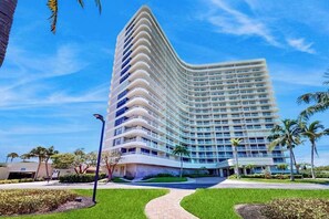 A multi-story hotel with a curved facade, a central entrance, and a well-maintained lawn. - Brilliant water view condo w/ shared pool, private washer &dryer, & sunset views (Marco Island)