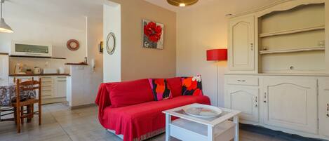 A living room with a red sofa, a white coffee table, and a kitchen area in the background.